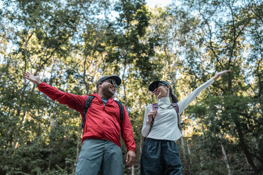 Couple Hiker man and woman climbing rocky mountain to explore cave hill and river enjoying outdoor adventure trekking, and nature travel. Two traveller and nature lover on an exciting hiking journey