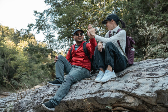 Couple Hiker man and woman climbing rocky mountain to explore cave hill and river enjoying outdoor adventure trekking, and nature travel. Two traveller and nature lover on an exciting hiking journey
