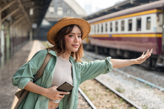 Freedom traveler beautiful woman at terminal train station. Happy tourist travel by train on vacation time holiday weekend trip. Female Backpacker arrival at platform railway.