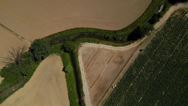 Aerial View of Farmland: An aerial perspective showcases the geometric patterns of cultivated fields, bordered by a meandering stream and lush green trees.