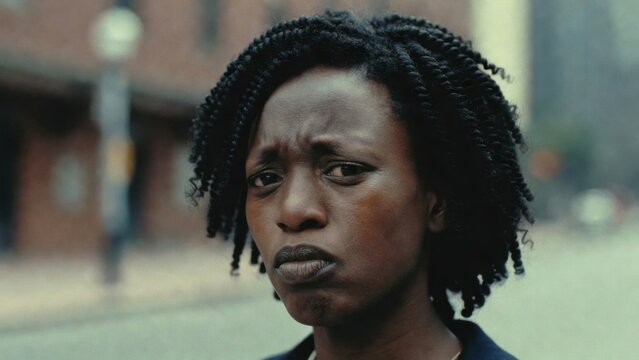Young black woman frowning with concern on city street