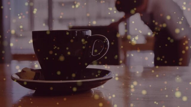 Dark cup centered with gold bokeh shining while barista noticing item bending reaching making drink