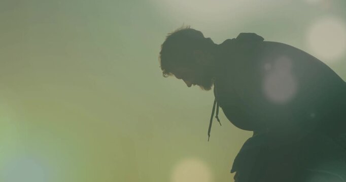 Man leaning forward in backlit film scene, sunlight causing lens flares drifting across silhouette