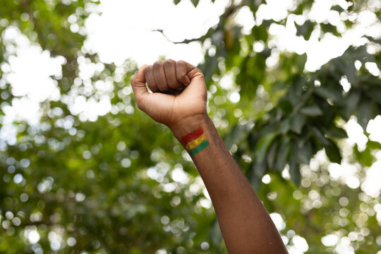 Man raising forearm and clenching fist at park displaying red yellow green wrist paint