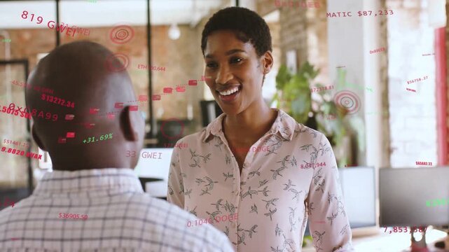 Woman speaking to man in biz office reviewing data, causing r or g HUDs between them, smiling laughi