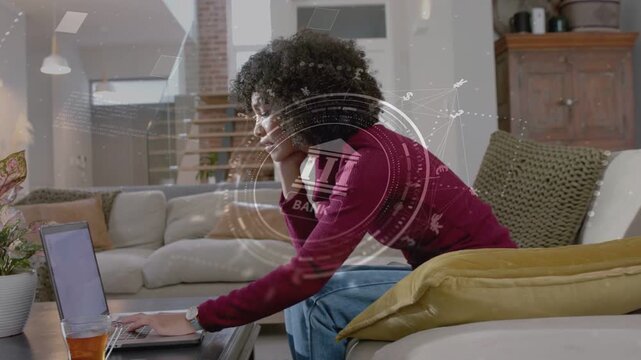 Woman leaning on sofa, typing on laptop and activating rotating bank HUD, verifying payment details