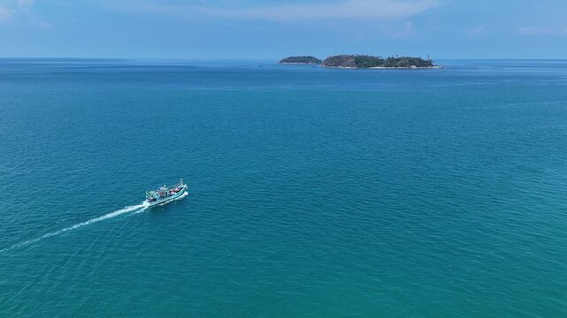 Fishing Boat Sails Across Vast Blue Ocean and Sea Towards Distant Island Under Clear Sky with Water and Horizon