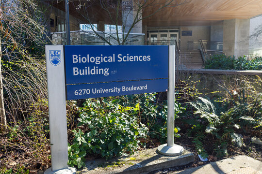 Blue UBC Biological Sciences Building entrance sign at 6270 University Boulevard, University of British Columbia campus on a sunny day.