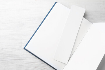 Obraz premium Book with white bookmark on light wooden table, top view. Space for text