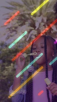 Vertical video: Girl dipping wand, blowing bubbles, neon streaks layering around for kids content