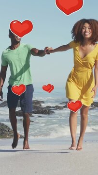 Vertical video: Couple from shore walking running holding loving hearts drifting over them for ads
