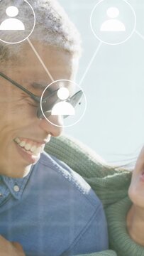 Vertical video: Couple hugging and laughing, laughter causing nodes appearing over faces in tech