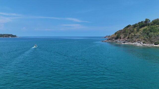 Serene View of Small Boat Sailing on Vast Blue Ocean with Rocky Coastline and Clear Sky in Distance