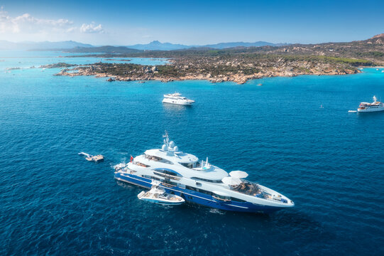 Aerial drone view of beautiful luxury yachts and boats in blue sea in summer. Sardinia island, Italy. Top down view of speed boats, turquoise water. Tropical landscape. Yachting. Seascape. Summer vibe