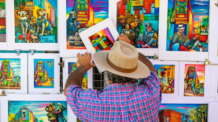 Local artist arranging vibrant colorful paintings of Caminito in the La Boca district oaf Buenos Aires, Argentina © Yuliko