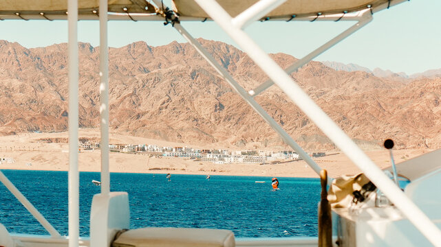 Tropical seaside with beach, ocean, umbrellas, yatch and summer vacation relaxation scenery