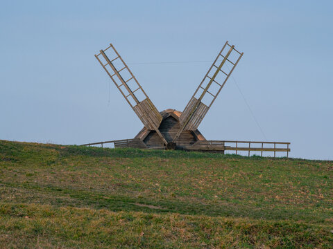 Outstretched sails of a historic windmill crowning a hilltop 