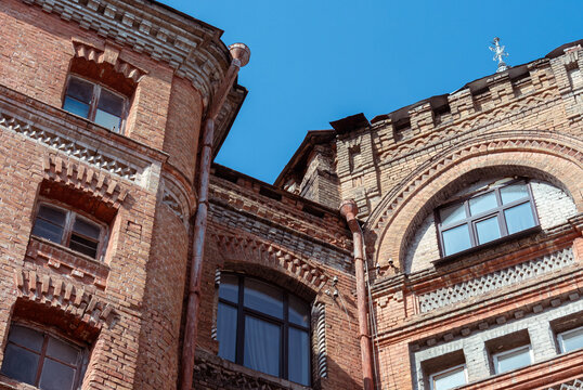 Ornate red brick turret and arched facade against deep blue sky 