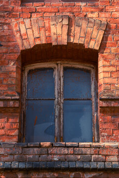 Weathered wooden window frame with crumbling paint in old brick facade 