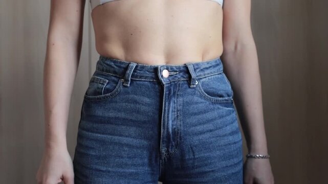 The girl does not fit into jeans, excess weight and sides on the stomach, slight obesity, the concept of weight loss.