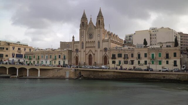 Neo-Gothic Carmelite Parish Church in Balluta Bay under cloudy sky, Malta.