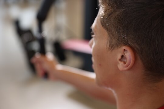 Man sweating while exercising with chest press machine in gym, closeup. Space for text
