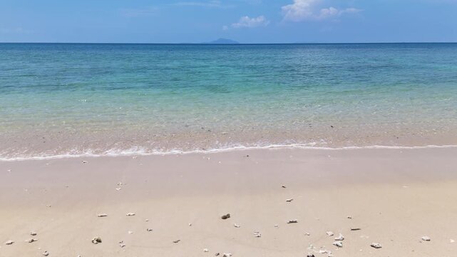 Serene Beach with Gentle Waves, Clear Blue Sky, and Distant Island Peaceful Atmosphere by Ocean Horizon