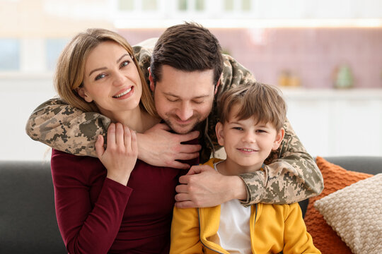 Man in military uniform hugging his family at home
