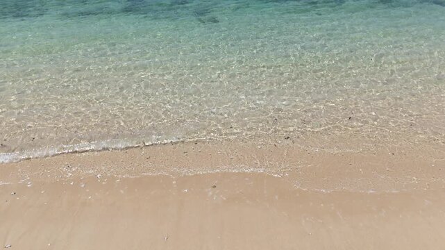 Serene Beach Scene Clear Blue Sea and Ocean Horizon with Gentle Waves and Distant Island Under Bright Sky and Clouds