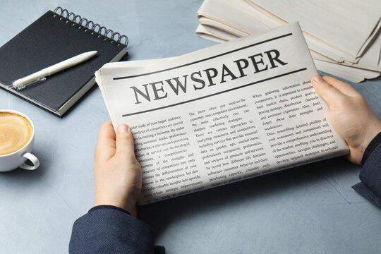 Man with newspaper at grey table, closeup