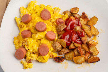 Fototapeta premium scramble eggs top with hot dogs and home fries