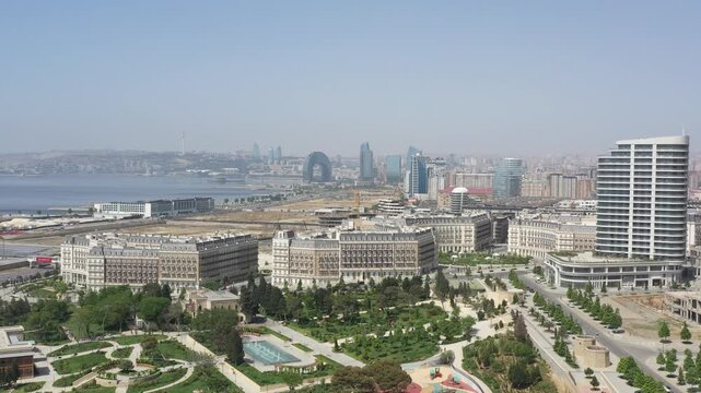 Drone panorama of landscaped park with lake and pathways in Baku, with modern skyline and Caspian Sea coastline in the background