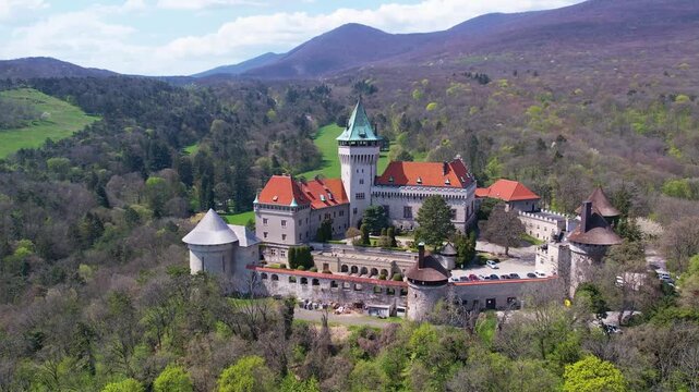 Aerial Smolenice Castle stands majestically amidst a vibrant sea of green, with its picturesque turrets and historic architecture framed by a perfect day. A serene oasis in the heart of Slovakia.