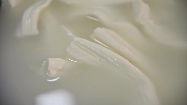 Stracciatella cheese preparation process with visible curds and whey