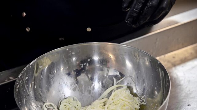 Chef prepares stracciatella cheese by stretching and pulling curds in a stainless steel bowl
