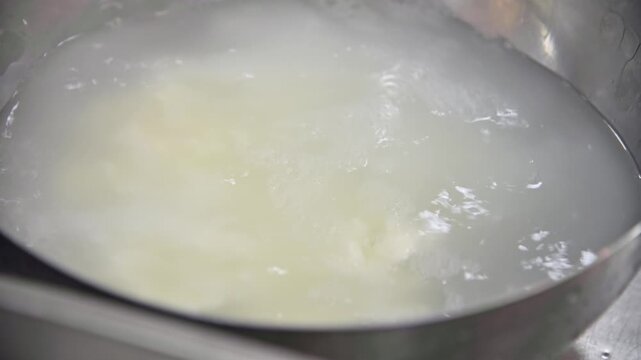 Stracciatella cheese preparation process in stainless steel bowl with water