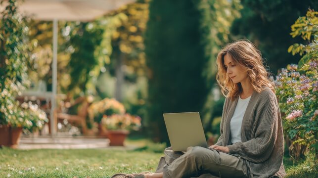 Female diversity. Human rights, equal opportunity concept. A woman sits on the grass in a garden, engrossed in her laptop. She wears a lightcolored.