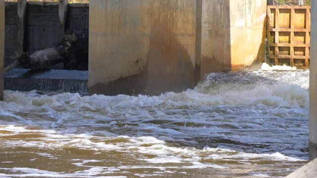 Water Rushing Through Old Concrete Dam Sluice Gate with White Foam and Turbulent Flow - River Dam Water Release and Hydraulic Infrastructure