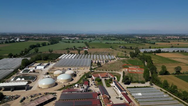 Aerial View of an Agricultural and Biogas Plant Facility: An expansive aerial perspective showcases a modern agricultural complex featuring numerous greenhouses, a biogas digester.