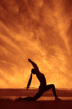 Anjaneyasana  New Moon Pose Woman stretching outdoors, fit female doing Crescent High Lunge pose,  Eight Point Moon at sunset, yoga exercise in nature, side view full length Evening sky background