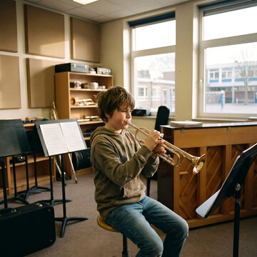 Teenage boy playing trumpet in music classroom during practice