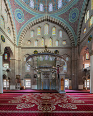 Obraz premium Interior of Burunguz Mosque, or Burunguz Camii, Kayseri, Turkey. Features ornate dome, vibrant stained glass windows, grand chandelier, and richly patterned red carpet