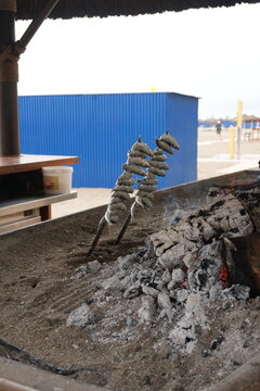 Traditional Spanish Espetos: Sardines grilling on skewers over open fire in a boat at Malaga beach, Andalusia.