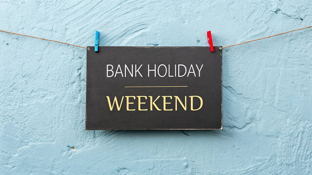 Black chalkboard sign featuring hand written gold letters announcing that a bank holiday weekend has finally arrived for everyone today