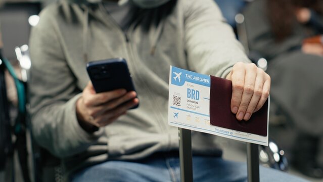 Waiting for plane arrival, boarding pass and man in airport checking flight itinerary on smartphone. Doing trip planning, passport document and passenger using phone, camera A