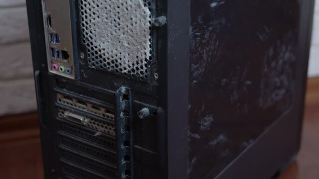 Dusty desktop computer case needing cleaning. Thick layer of dust and grime covering the back panel and cooling fan grill of a neglected desktop computer, highlighting the need for regular maintenance