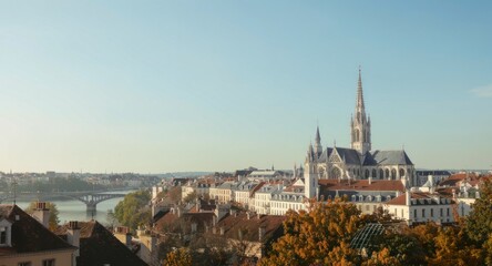 Obraz premium Picturesque cityscape with grand cathedral, river, bridge, and autumn foliage under blue sky