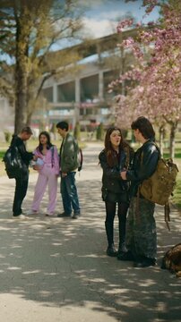 High school friends engage in cheerful conversation outdoors on a sunny day. Young students enjoy talking and socializing together in a park.