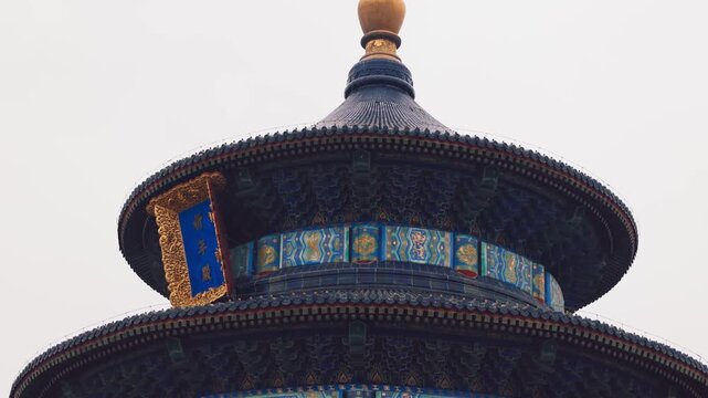 Temple of Heaven with layered blue roof with ornate painted panels and bright golden finial presents vivid example of traditional Chinese craftsmanship under soft sky, Beijing, China, 4k