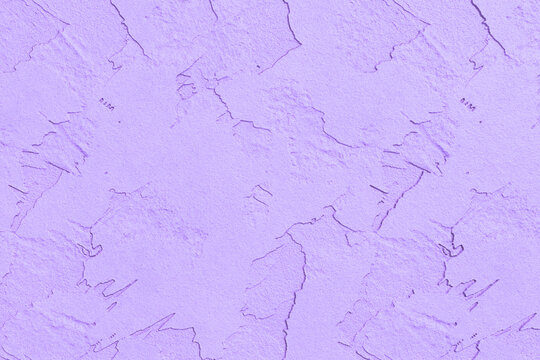 A soft lavender stucco wall shows a rough and cracked textured surface.